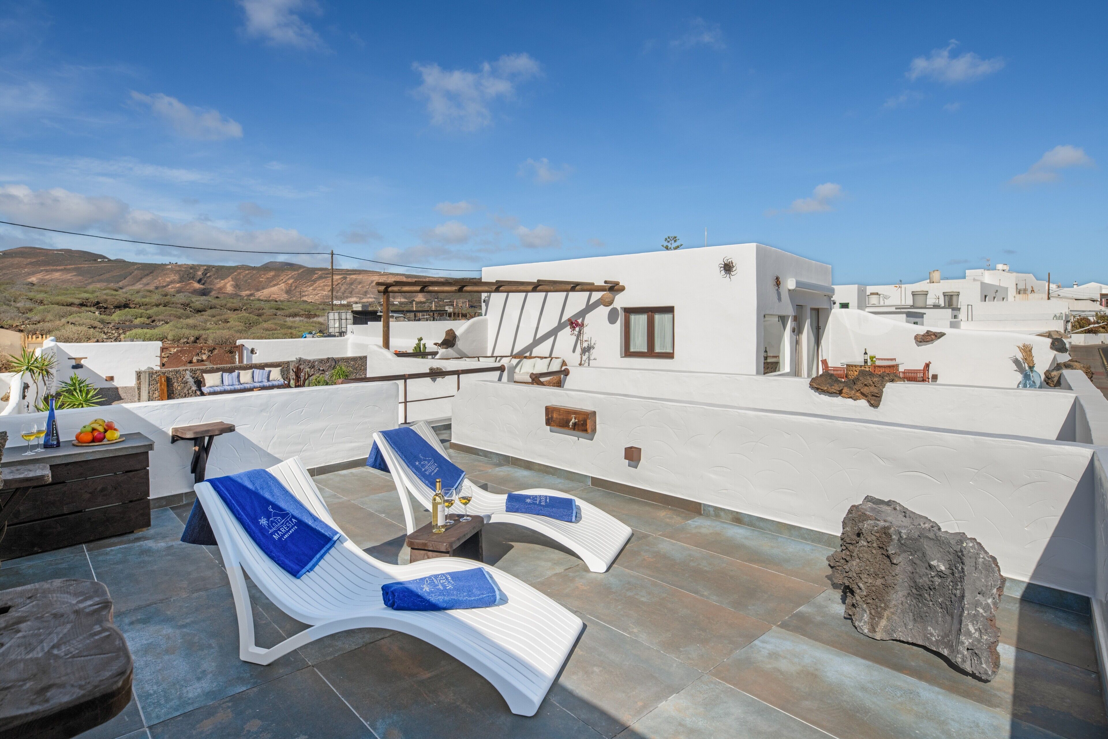 Una terraza en la azotea con sillones de descanso, un pérgola y vistas del paisaje circundante.