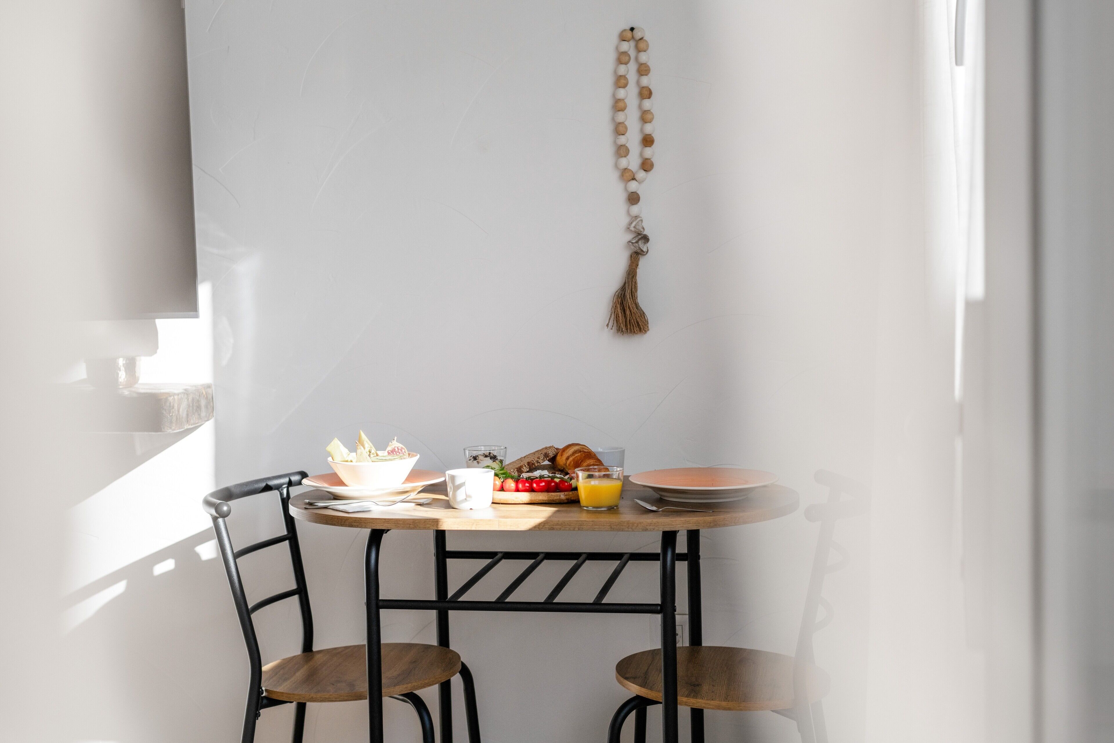 A dining table with breakfast items, two chairs, and a hanging decorative object.