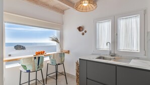 A kitchen with a view of the sea, a bar area with two chairs, and a modern light fixture. - Vacation Apartment 'Maresía' with Sea View, Wi-Fi and Air Conditioning (Haría)
