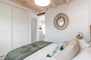 A bedroom with a bed, a circular mirror, a bedside lamp, and a door leading to another room. - Vacation Apartment 'Maresía' with Sea View, Wi-Fi and Air Conditioning (Haría)