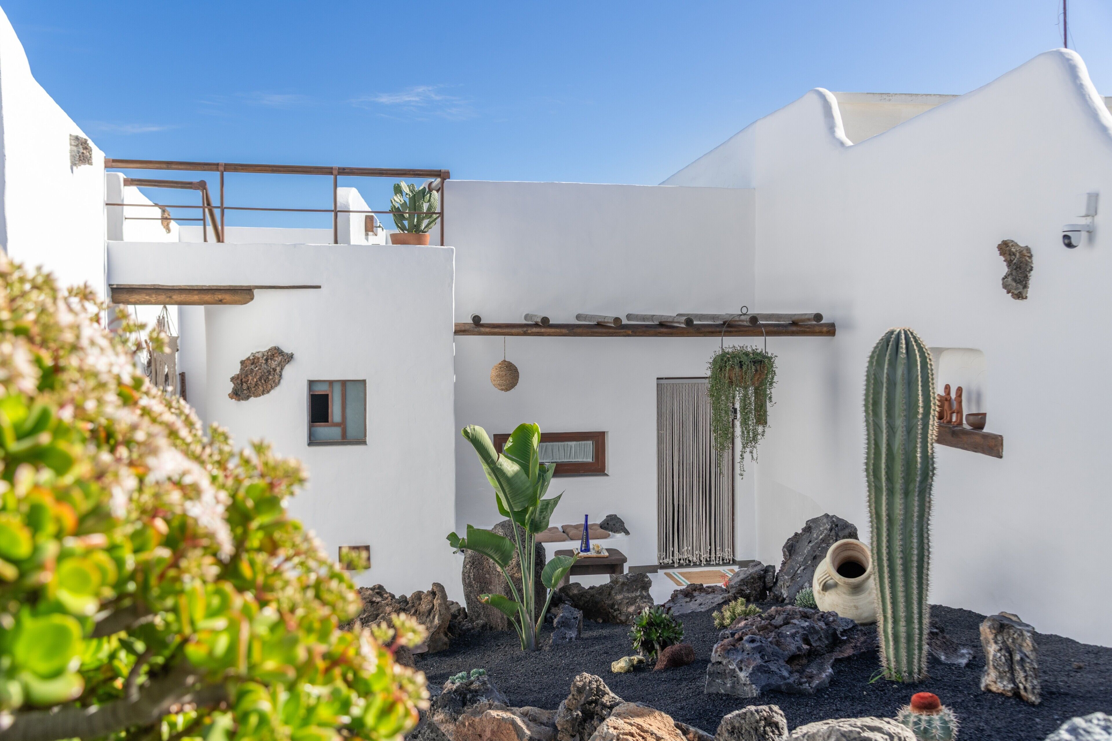 Een wit gebouw met een balkon, een cactus en een rotstuin.