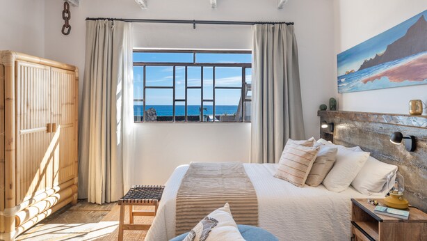 A bedroom with a large bed, a view of the sea through a window, and a painting on the wall. - Vacation Apartment 'Rumor del Mar' with Sea View, Wi-Fi and Air Conditioning (Haría)