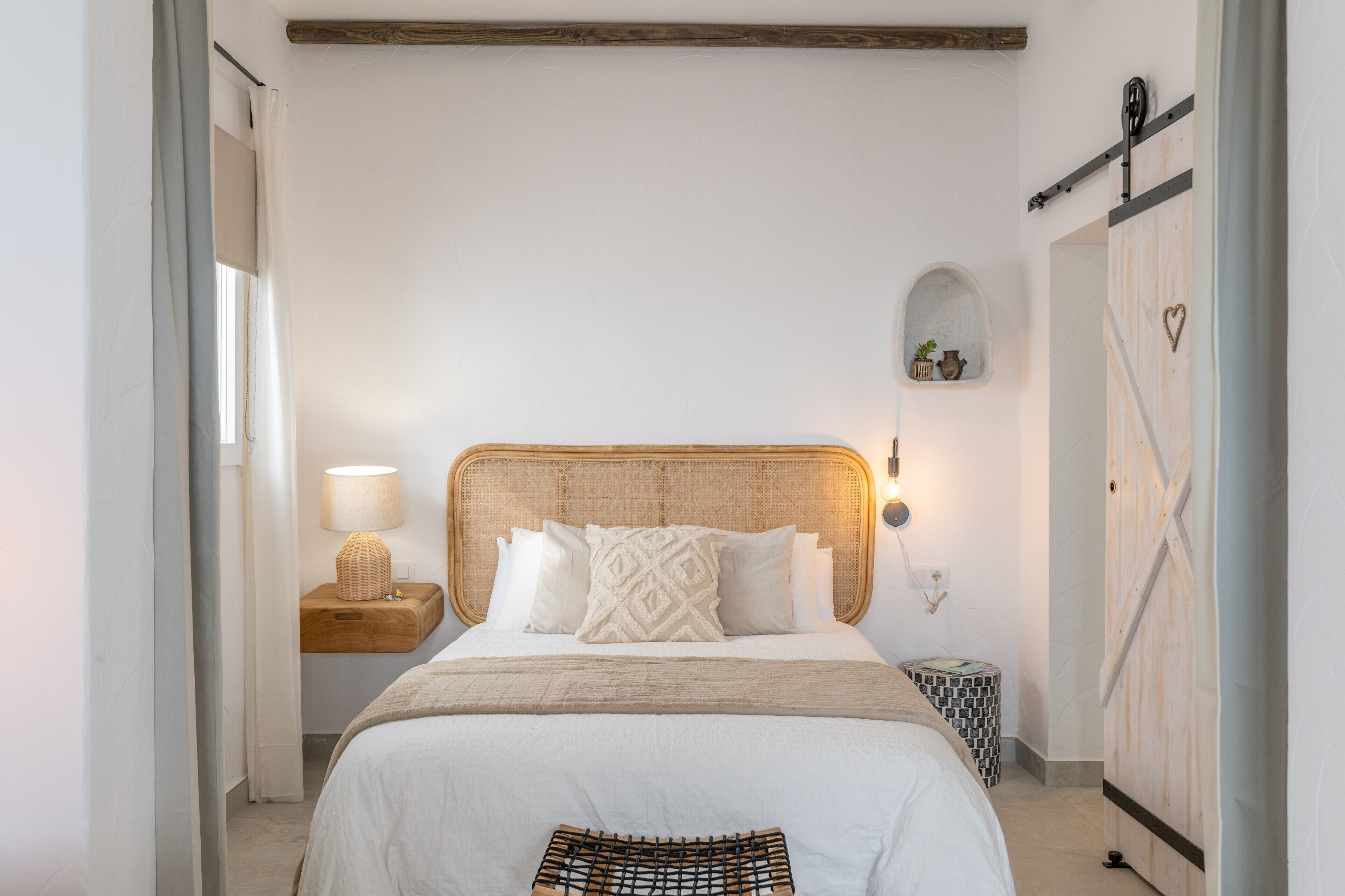 Ein Schlafzimmer mit Bett, Nachttisch, Lampe, Wandregal und Kleiderschrank.