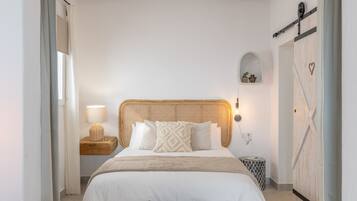 Ein Schlafzimmer mit Bett, Nachttisch, Lampe, Wandregal und Kleiderschrank.