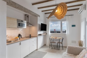 A modern kitchen with a built-in oven, a microwave, and a large window overlooking the sea. - Vacation Apartment 'Salitre' with Sea Views, Wi-Fi and Air Conditioning (Haría)