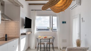 Et moderne køkken med et fladskærms-TV, et spiseområde med bord og stole, og et stort vindue med udsigt.