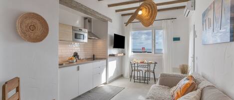 Una cucina moderna con mobili bianchi, un'area pranzo con tavolo e sedie, un divano e un'ampia finestra con vista.