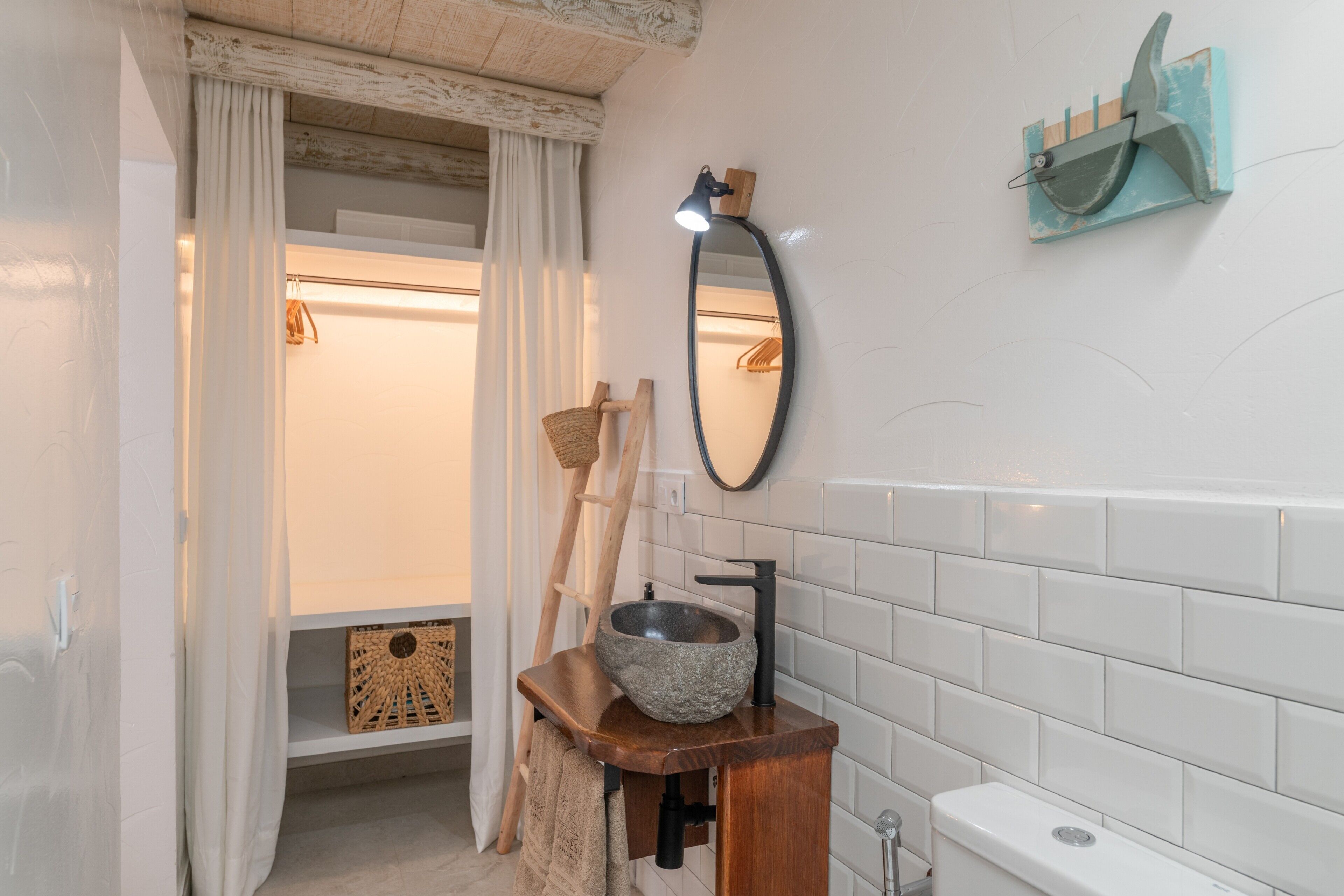 Un bagno con una vasca in pietra, uno scaffale in legno, un porta asciugamani e uno specchio a parete.