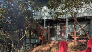 Ein Haus mit Feuerstelle und roten Stühlen im Garten.