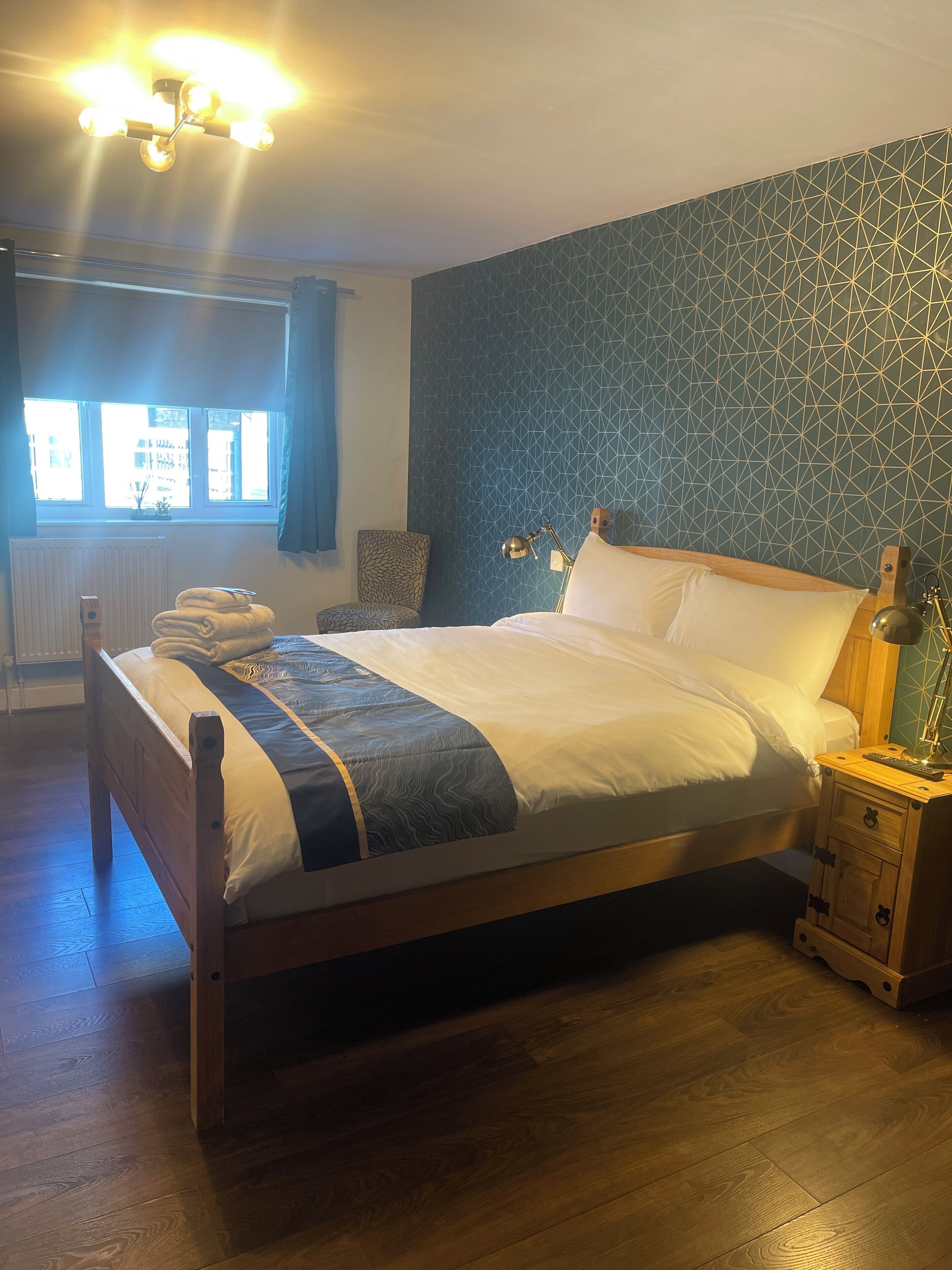 A neatly made bed with a patterned bedspread, a bedside lamp, and a wooden nightstand.