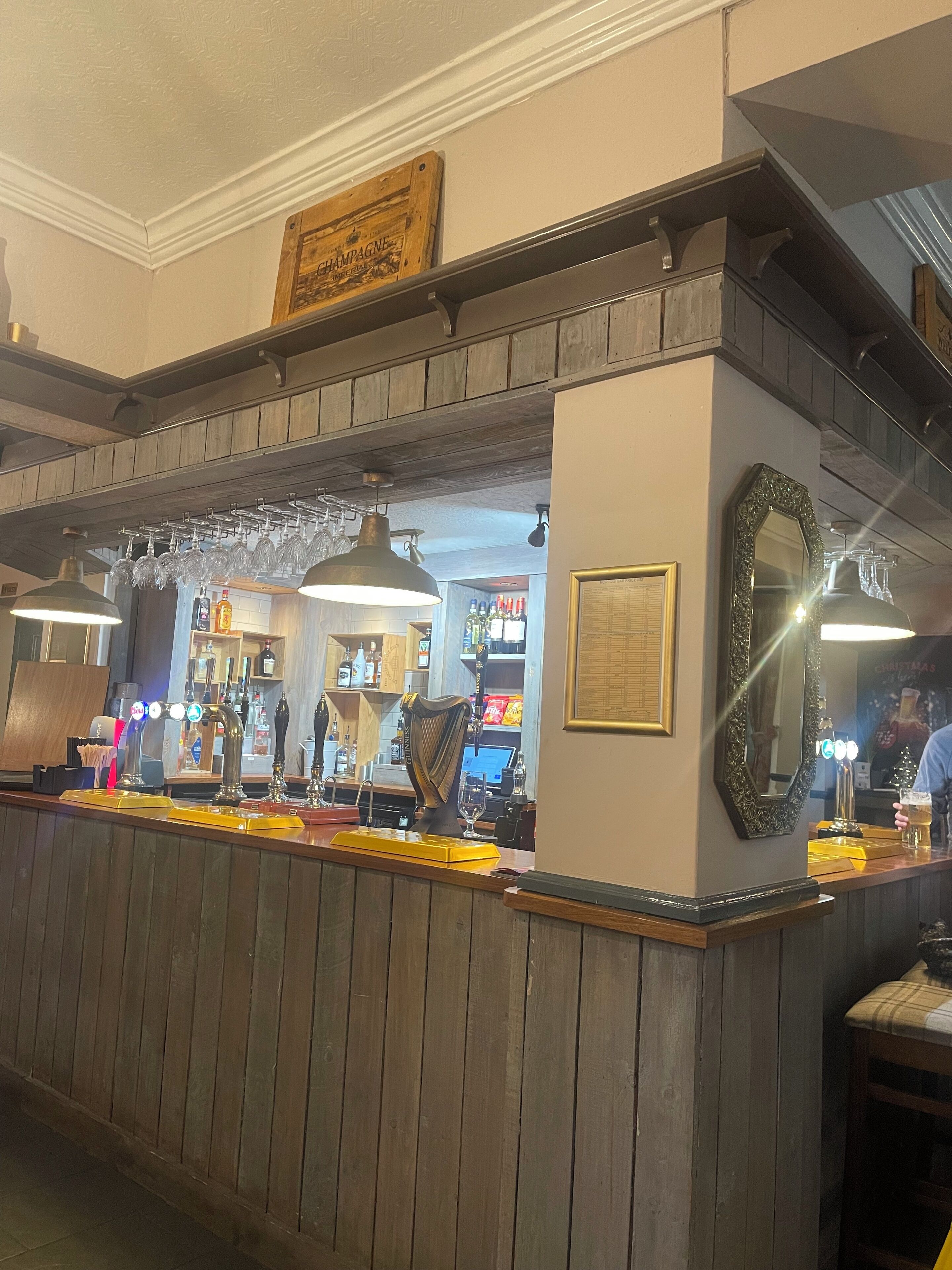 A bar area with wooden paneling, a beer tap, and a mirror.