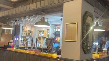 A bar area with wooden paneling, a beer tap, and a mirror.