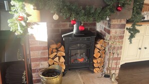 Una chimenea con un árbol de Navidad, un televisor mostrando un menú y una pared de ladrillo.