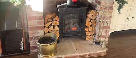 A fireplace with a Christmas tree, a TV displaying a menu, and a brick wall.