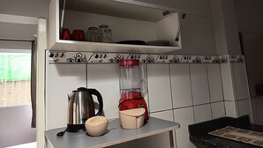 A kitchen with a white cabinet, a kettle, a blender, and a cup on the counter. - Vacation home in the south of the island, close to beaches and the airport.  (Florianópolis)