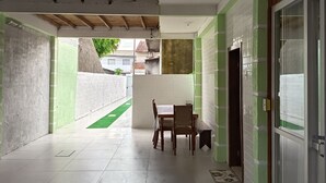 A covered outdoor area with a table and chairs, a tiled floor, and a green artificial grass path. - Vacation home in the south of the island, close to beaches and the airport.  (Florianópolis)