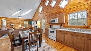 A log cabin interior with a dining area, kitchen, and living room. - Cozy Cabin in Mountains | Firepit | Views | Games (Helen)