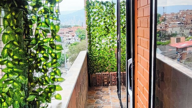 A balcony with a stone floor, a wooden ceiling, and a view of a cityscape.