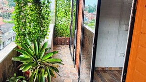 A covered balcony with stone flooring, potted plants, and a view of the cityscape.
