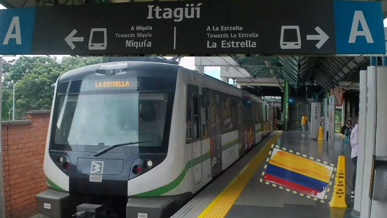 Un quai de gare avec un train portant l’inscription « LA ESTRELLA » et des panneaux indicateurs indiquant les directions vers « Itagui » et « A La Estrella ».