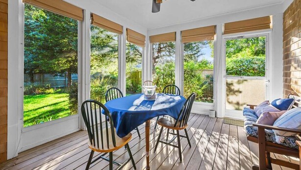 A sunroom with a table and chairs, large windows, and a ceiling fan. - Prime Meridian: 033-Ba  Spacious and Special, Walk to Beach, Harbor, Village (Barnstable)