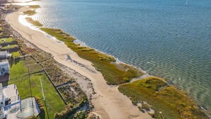An aerial view of a coastal area with a sandy beach, a small boat, and a house near the water. - Prime Meridian: 033-Ba  Spacious and Special, Walk to Beach, Harbor, Village (Barnstable)