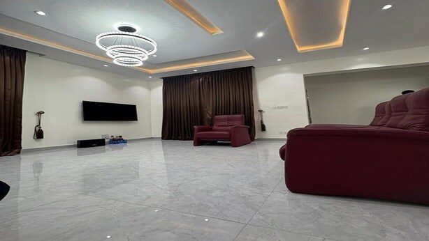 Uma sala de estar moderna com televisão de tela plana, um sofá vermelho, uma poltrona vermelha e um lustre.