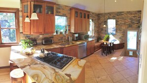 A kitchen with wooden cabinets, a granite countertop, a stove, and a sink. - 6-Bedroom Tudor in the Historic District (Salt Lake City)
