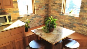A kitchen with a marble countertop, wooden cabinets, a microwave, two stools, and a potted plant. - 6-Bedroom Tudor in the Historic District (Salt Lake City)