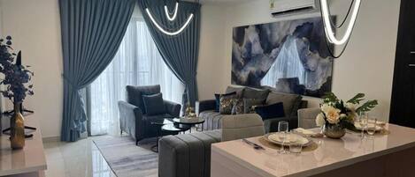 A modern living room with a sofa, a coffee table, and a dining area with a table set for two.