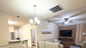 A spacious living room with a dining area, a large flat-screen TV, and a ceiling fan. - Cozy 3BR Retreat with DreamCloud Beds near Downtown Dallas (Dallas)