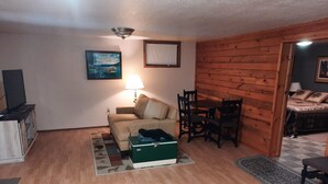 A cozy living room with a sofa, a small table, and a television.