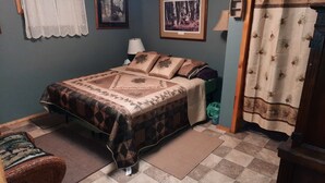A bedroom with a bed, a nightstand, a chair, and a window with curtains.