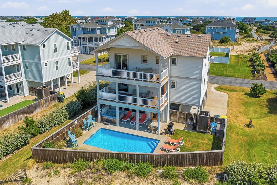 A multi-story residential building with a swimming pool, balconies, and a fenced backyard.