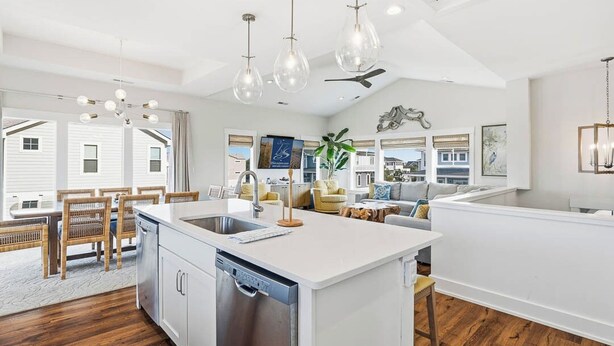 A modern kitchen with a central island, white cabinetry, and a dishwasher. There are hanging light fixtures and a ceiling fan. - Summer Moon | 1,615 ft to the beach | Private Pool, Hot Tub, and Dog Friendly (Corolla)