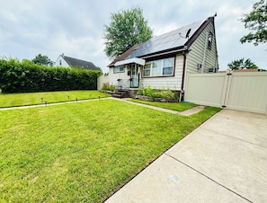 A residential house with a well-maintained lawn, a front porch, and a white fence. - Spacious, Charming 4BR, 2BA Glen Burnie Home, Sleeps 9 (Glen Burnie)