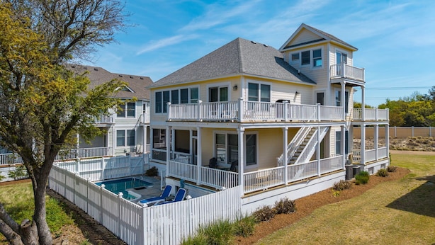 Une maison à deux étages dotée d’un balcon, d’une piscine et d’une terrasse couverte.