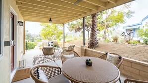 Veranda coperta con mobili in vimini, una ventola a soffitto e vista sul giardino.