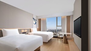 A modern hotel room with two beds, a small table, a TV, and a city view. - Fairfield by Marriott Changchun Jingyue High-Tech Zone (Changchun)
