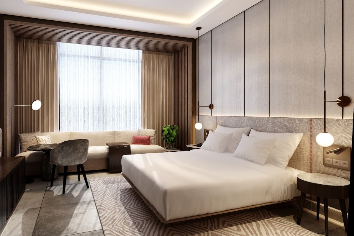 A modern hotel room with a large bed, a sofa, a desk, and a TV.