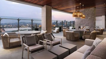 Un'area lounge esterna moderna con posti a sedere, un tavolo rotondo e vista sulla città.