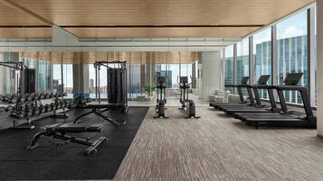 A modern gym with cardio equipment, weight machines, and dumbbells.