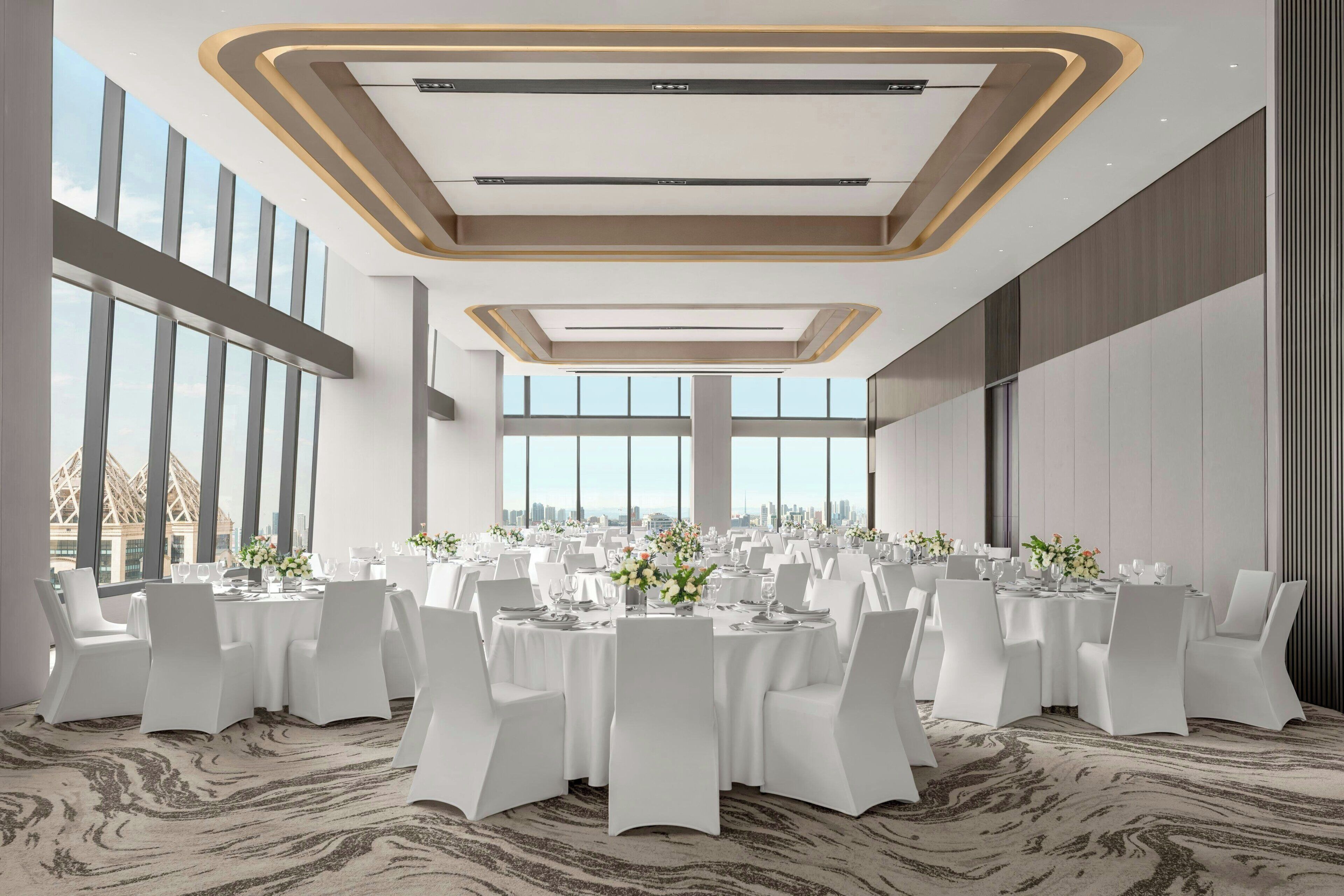 A spacious conference room with a high ceiling, large windows, and a modern design.