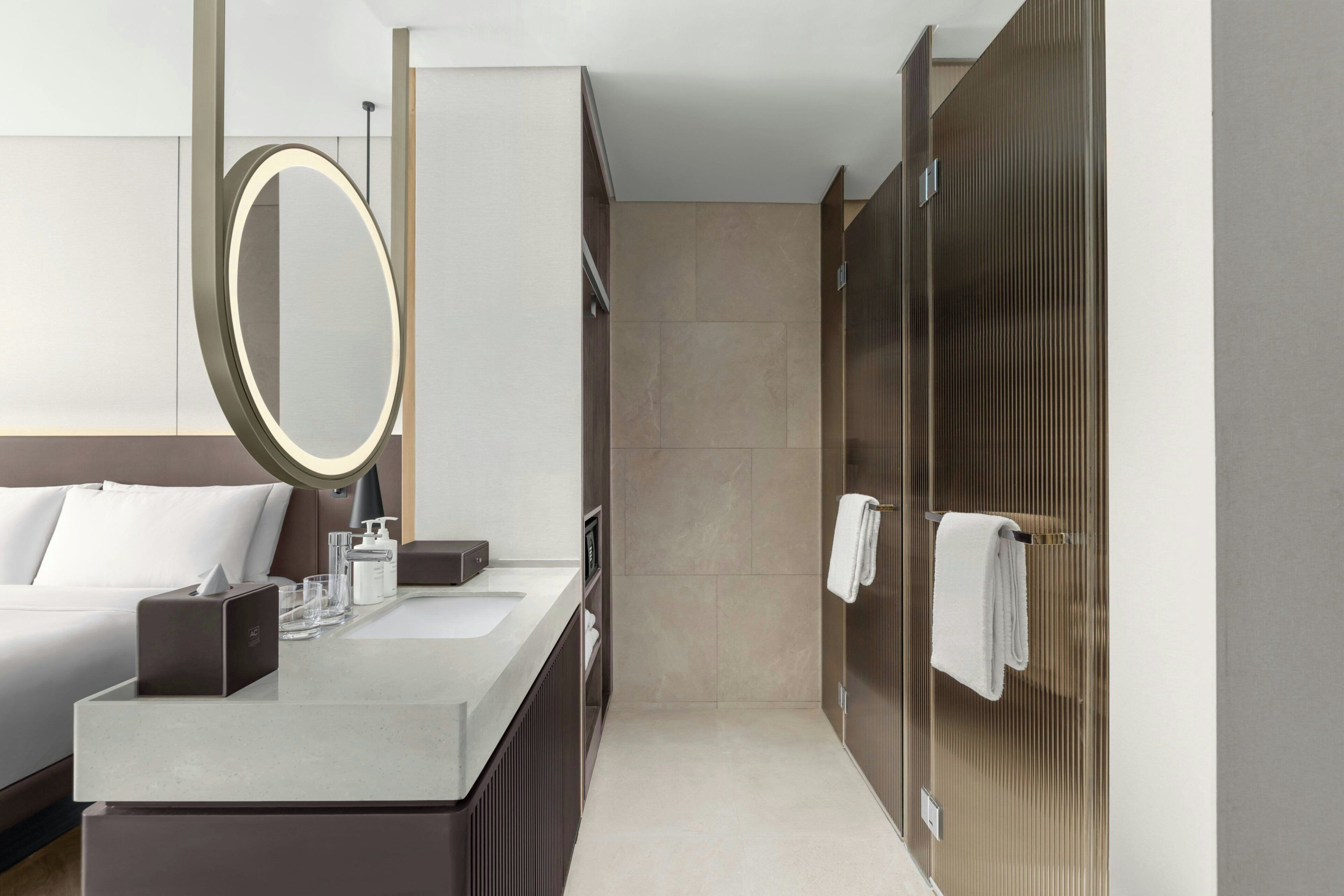 A modern bathroom with a large mirror, a sink with toiletries, and a shower area.