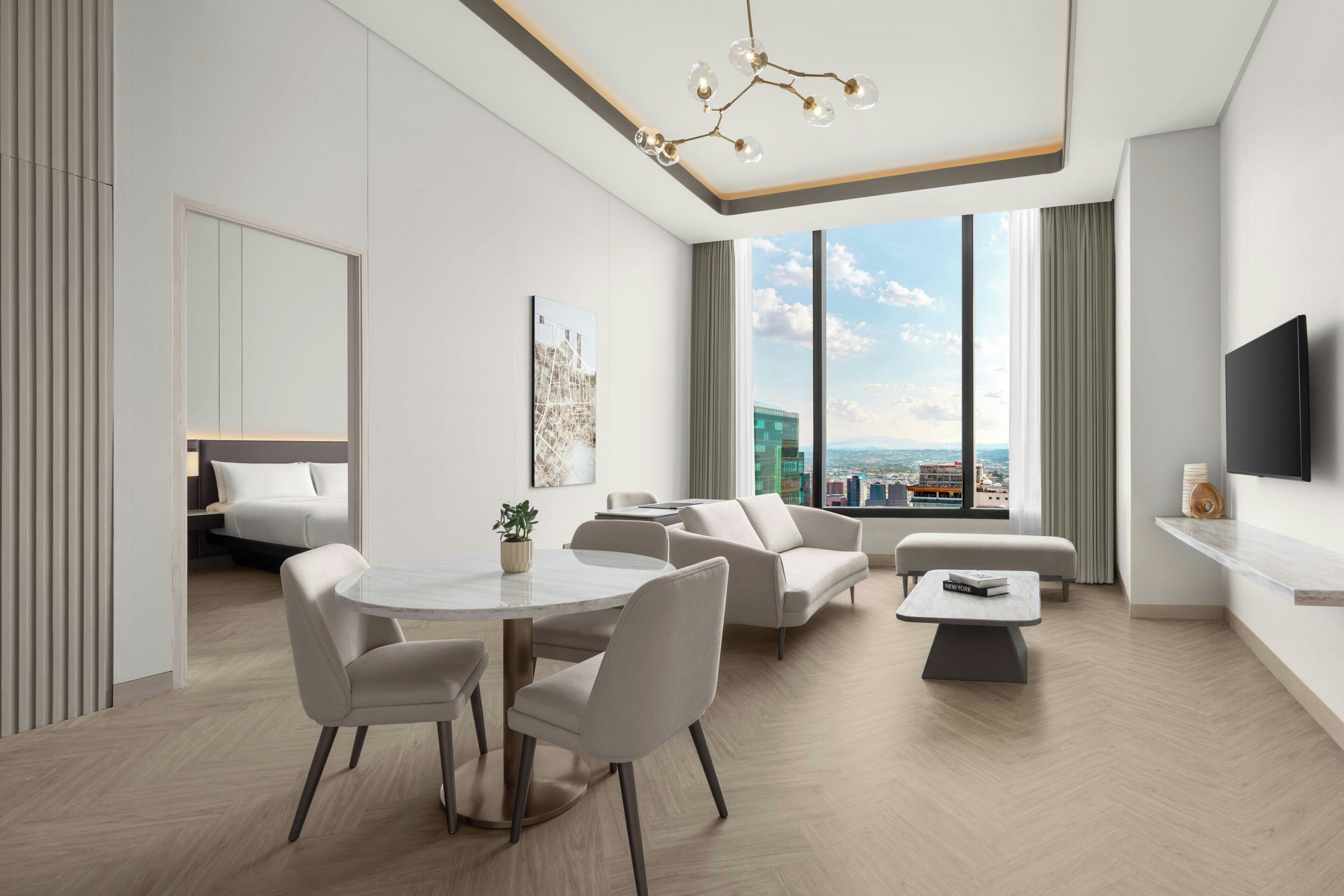 Een moderne woonkamer met een eethoek, grote ramen en uitzicht op de stad.