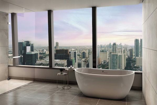 Un baño moderno con una bañera grande, una mesita pequeña y vistas a un paisaje urbano a través de amplios ventanales.