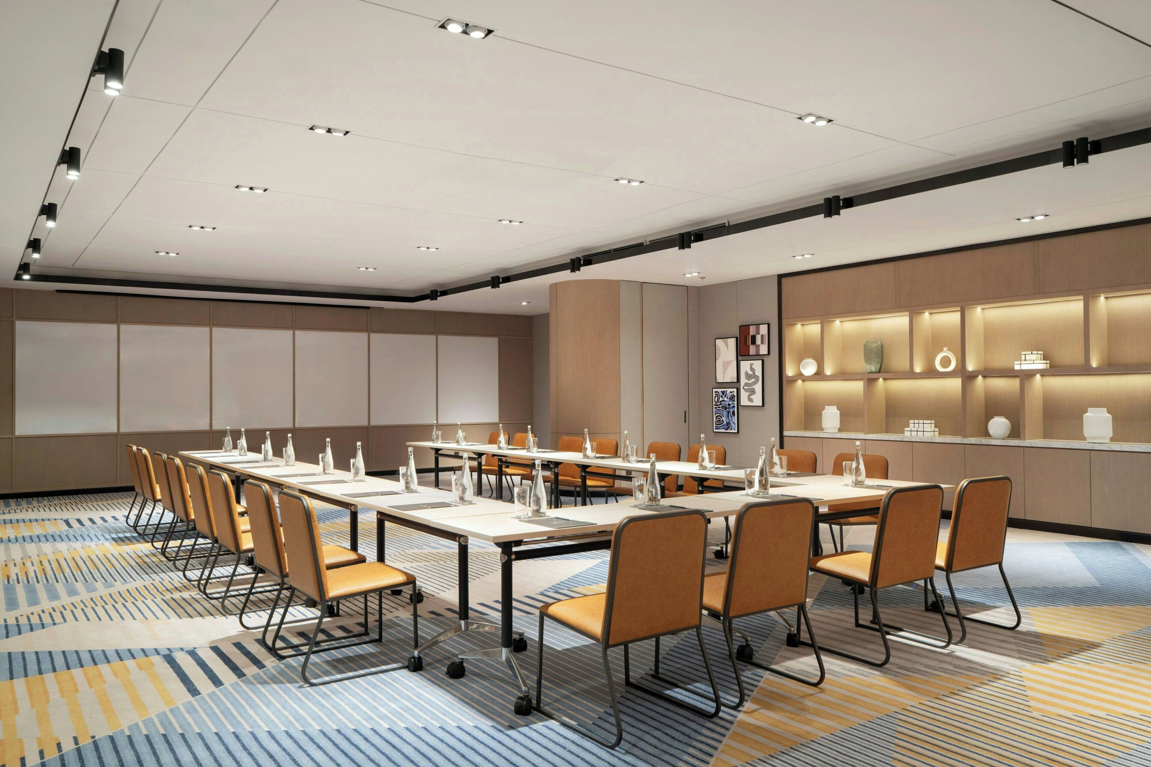 A conference room with a long table, chairs, and a carpeted floor.