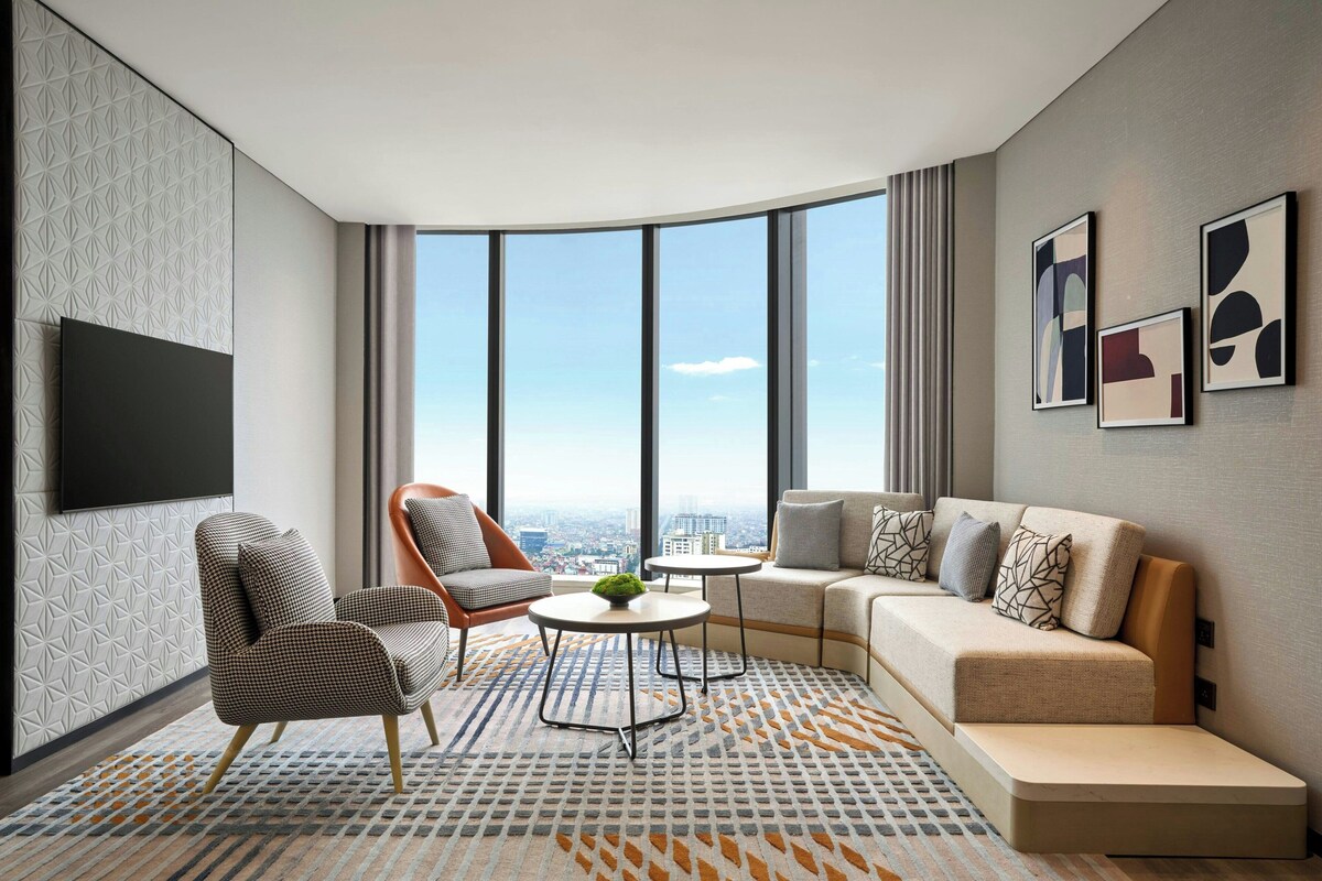 A modern living room with a sofa, armchairs, a coffee table, and a TV mounted on the wall.