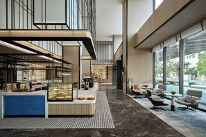 A modern hotel lobby with a central counter, seating area, and large windows. - Sheraton Vinh (Vinh)