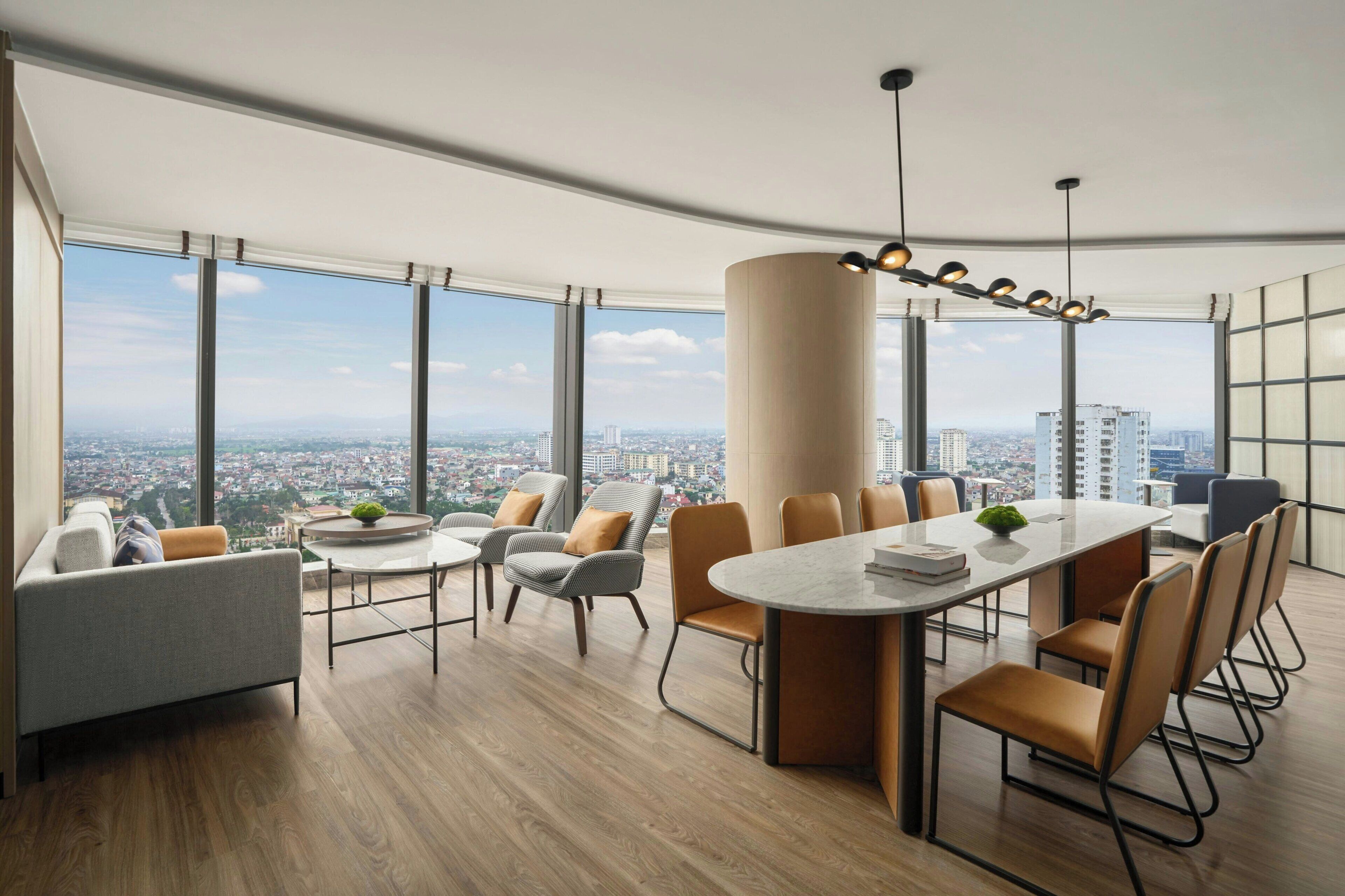 Una sala de conferencias moderna con vistas panor ámicas de la ciudad, una gran mesa central y asientos cómodos.